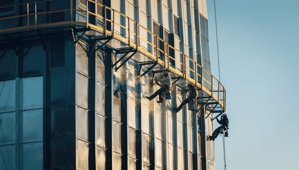 Industriekletterer am Seil die Metallbeschichtung auftragen